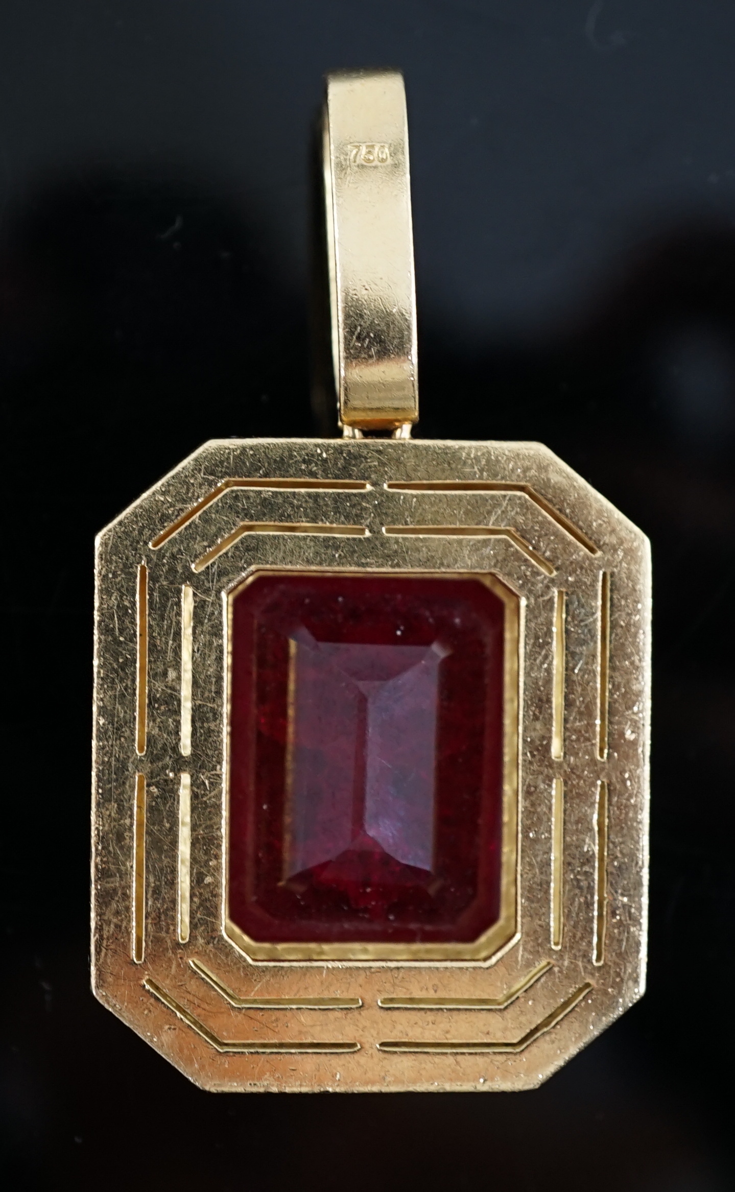 A large modern 18ct gold and single emerald cut synthetic ruby set pendant, bordered by three concentric bands of round brilliant cut diamonds